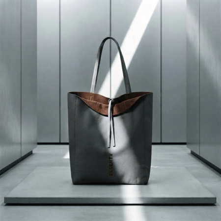 GREY MINIMALIST TOTE BAG FROM CYBER MOOD COLLECTION WITH DARK MORO BROWN LINING PLACED ON A BRUTALIST CONCRETE PODIUM
