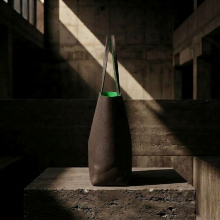 SIDE VIEW OF MORO MINIMALIST TOTE BAG WITH BRIGHT GREEN SUEDE LINING ON A BRUTALIST CONCRETE PODIUM